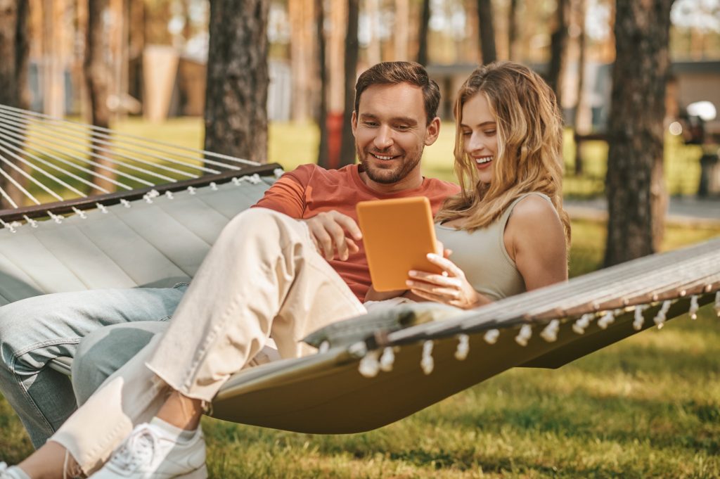 Young beautiful couple with tablet on hammock